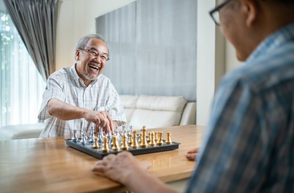 Two men enjoy playing chess together in a memory care community.