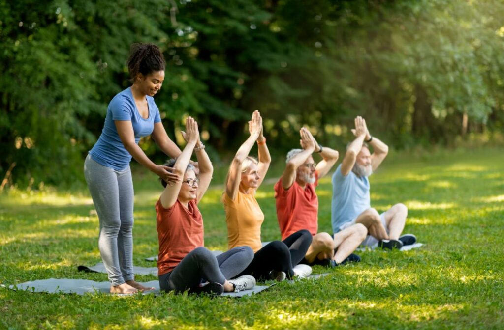 Older adults practicing yoga outdoors with the guidance of an instructor
