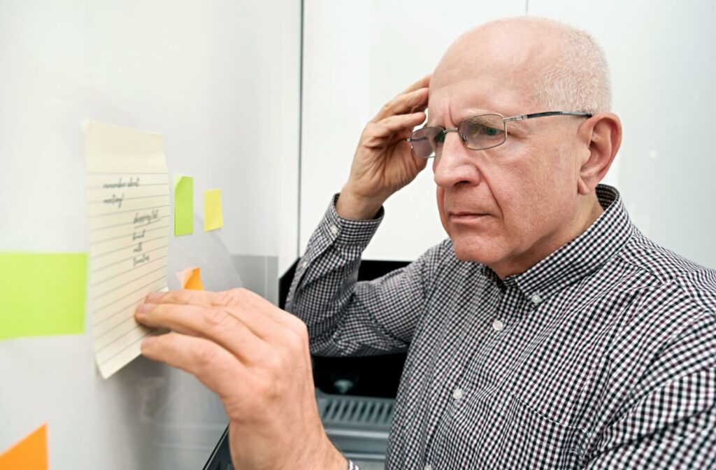 An older adult reading a note they left themselves on the fridge to address their poor memory.