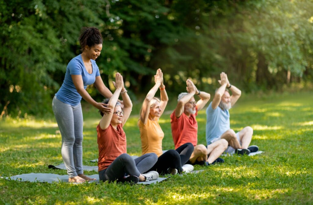 Older adults practicing yoga outdoors with the guidance of an instructor