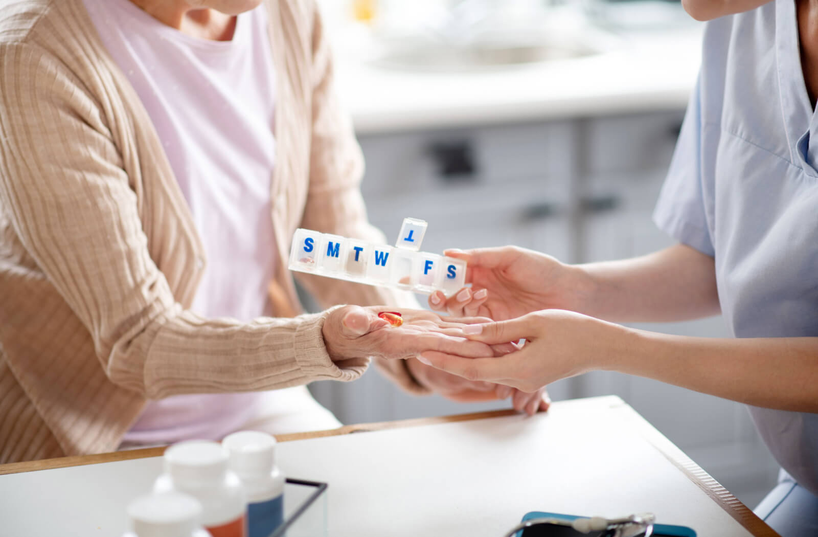 A proficient caregiver is dispensing medication to an older adult in her residence.