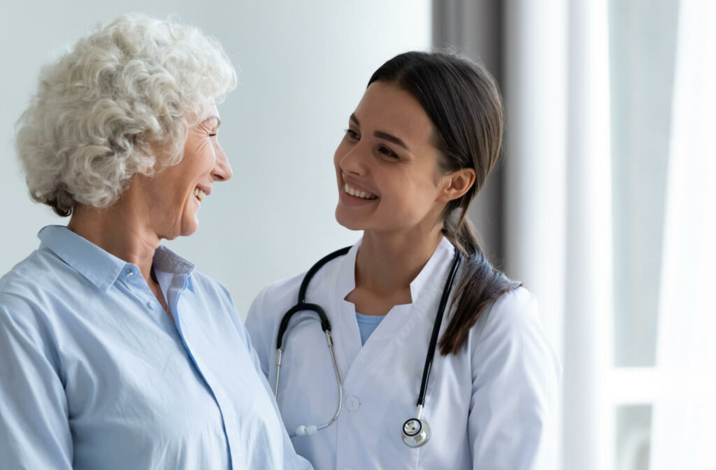 A caregiver smiles at an older adult with dementia in memory care after a health checkup